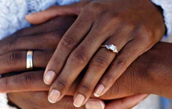 a couple's hands clasping with wedding bands visible