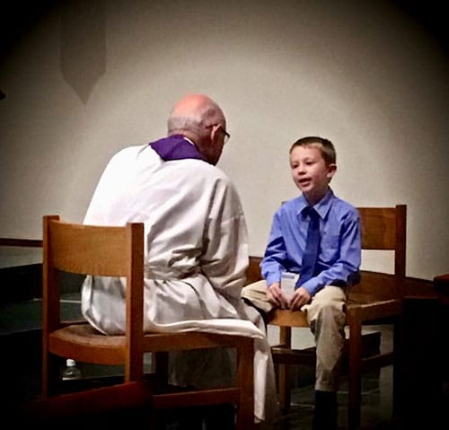 Young boy in confession with priest.