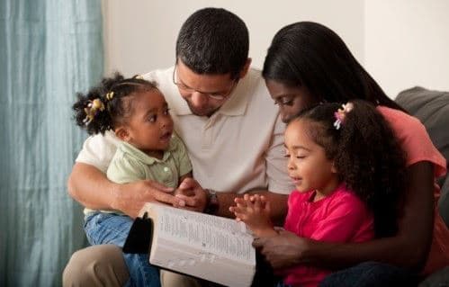 african american family reading the bible together.