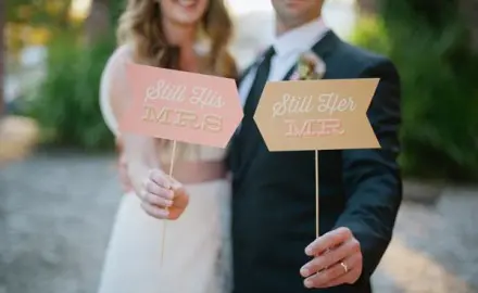 bride and groom holding signs that say "I'm his MRS. and I'm her MR."