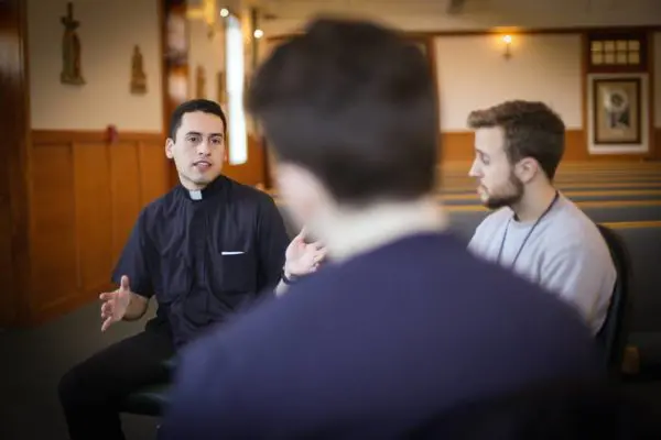priest talking to young men.